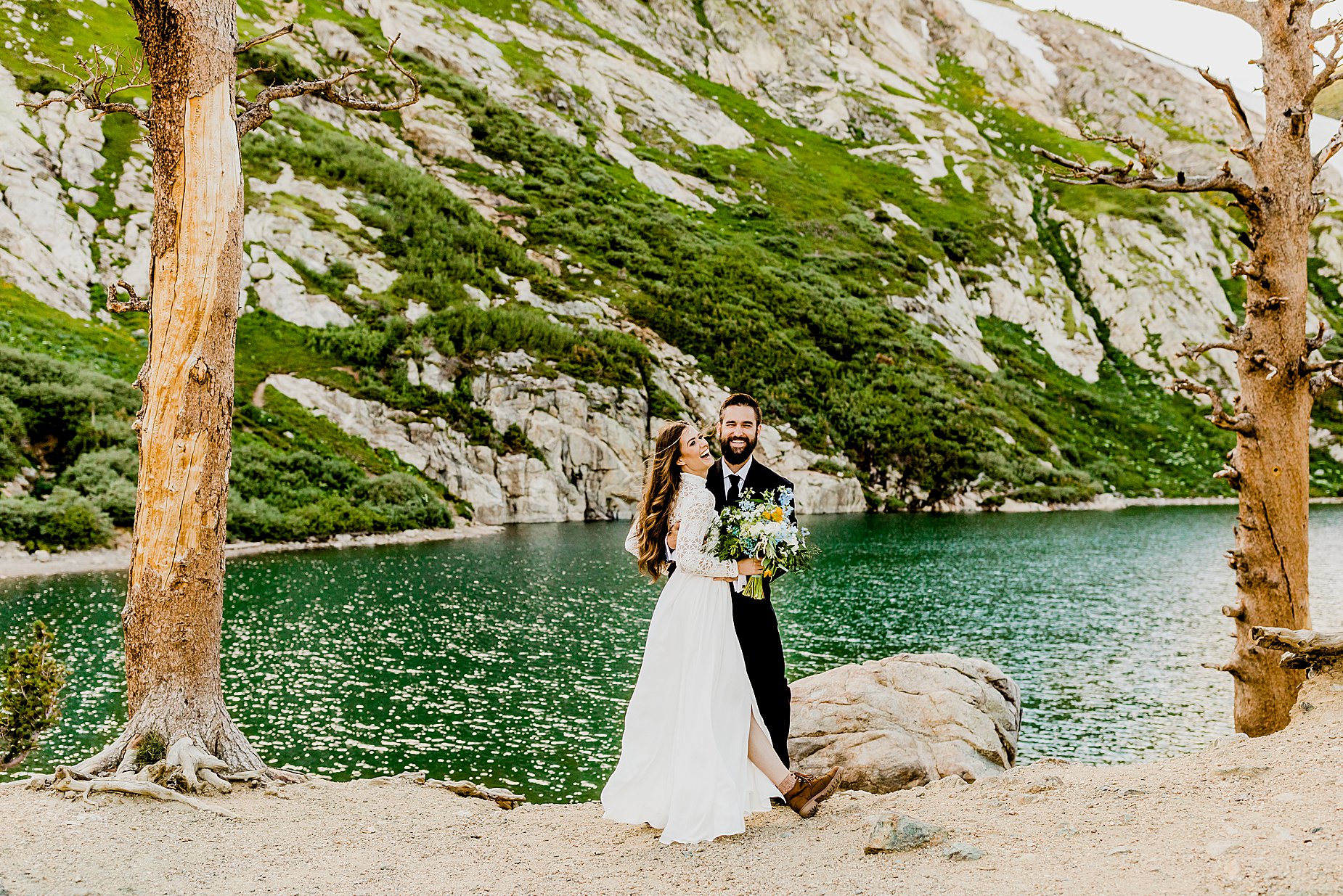 bride and groom embrace in front of beautiful colorado alpine lake for their elopement