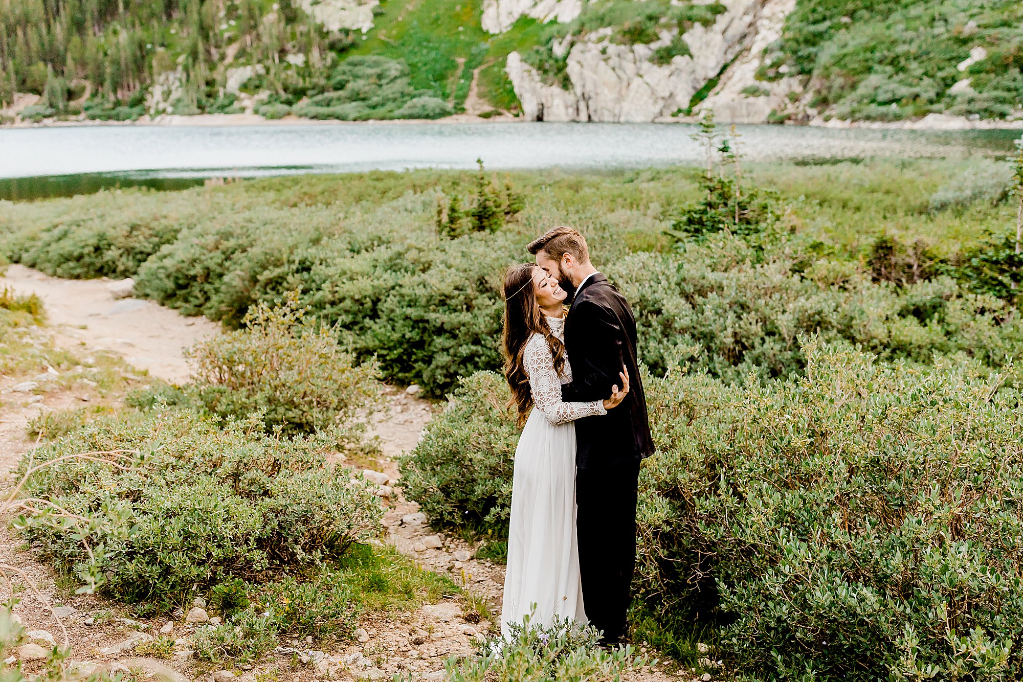 couple embraces in front of stunning colorado lake and glacier for their outdoor colorado adventure elopement