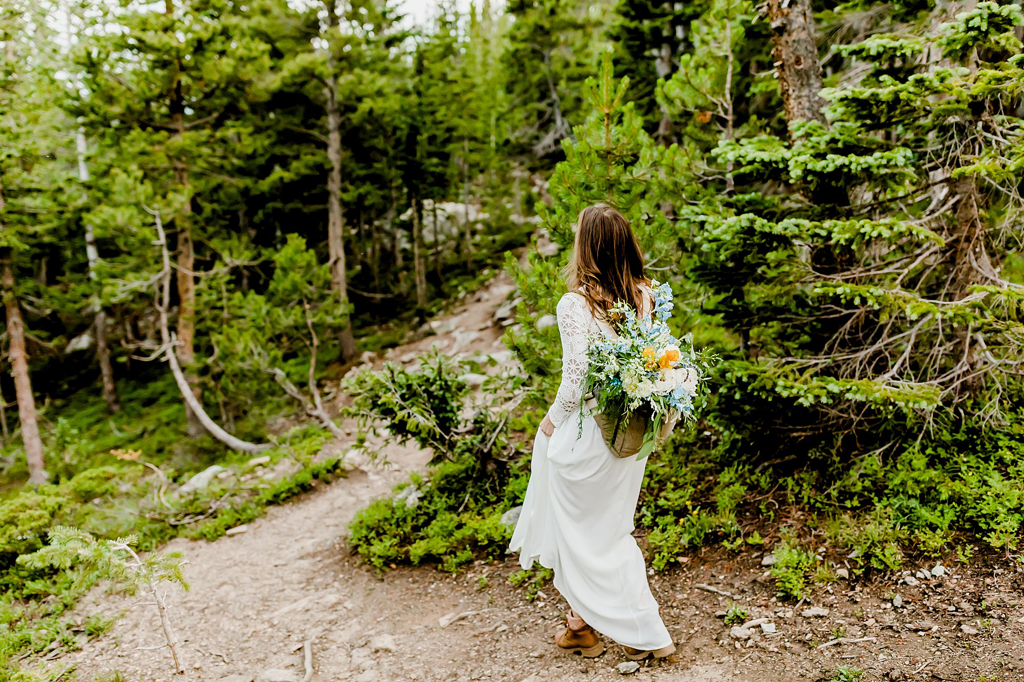 bride and groom hike back after their colorado adventure elopement surrounded by a gorgeous forest and mountains