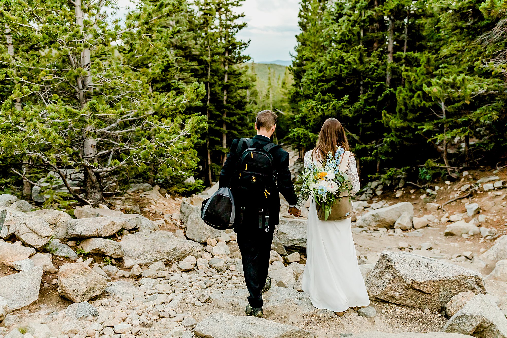 bride and groom hike back after their colorado adventure elopement surrounded by a gorgeous forest and mountains