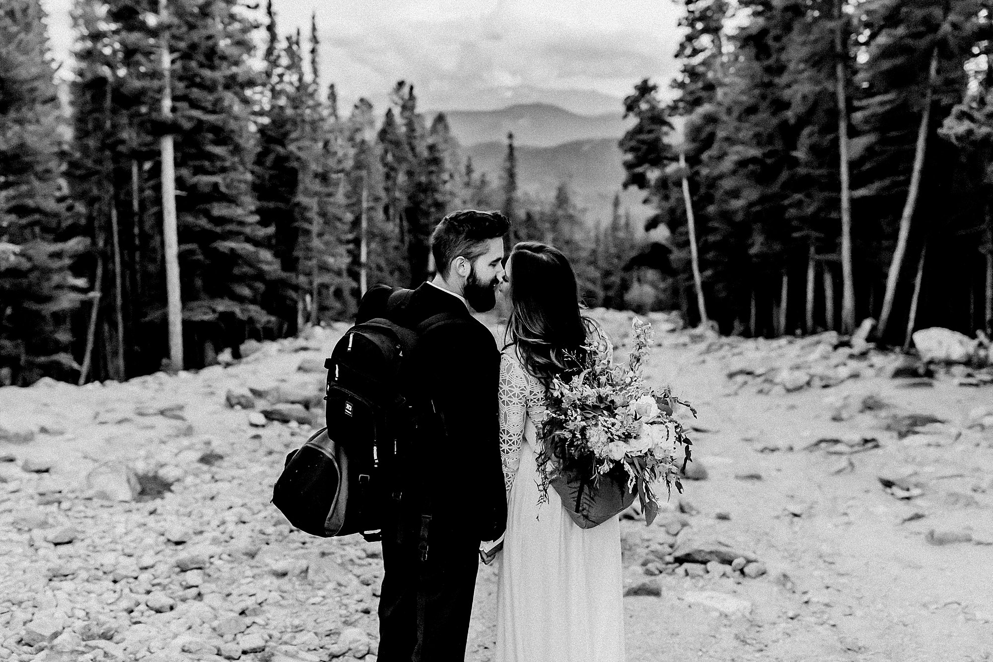 bridal bouquet in bride's backpack as the couple hikes back from their adventure elopement