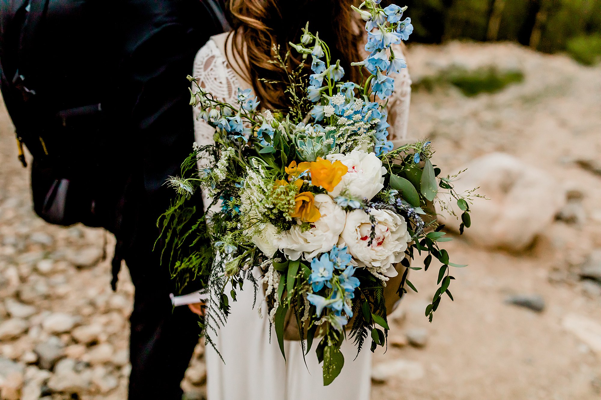 bridal bouquet in bride's backpack as the couple hikes back from their adventure elopement