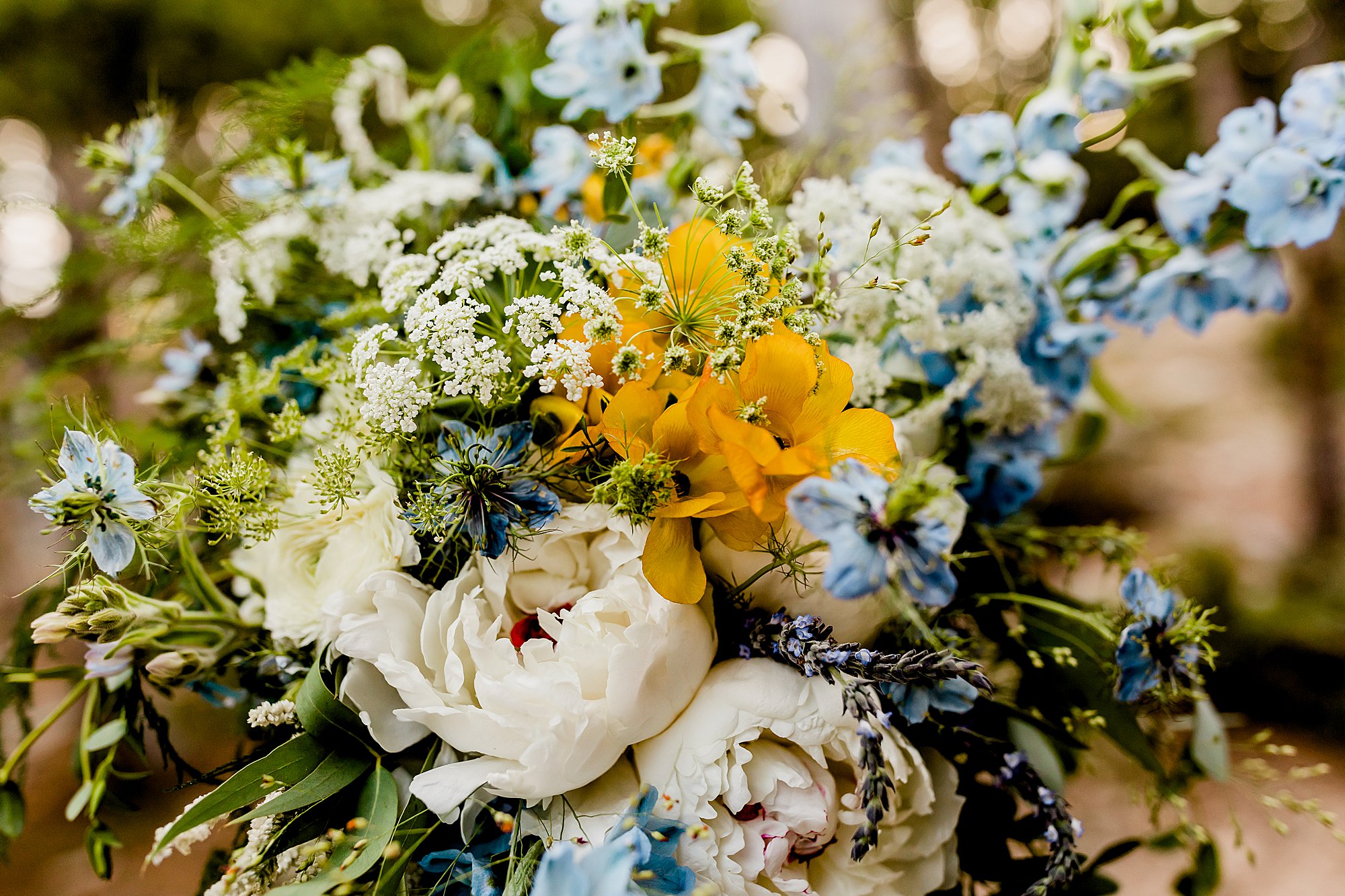 beautiful bridal bouquet with different types of flowers in blue, white, yellow, and green