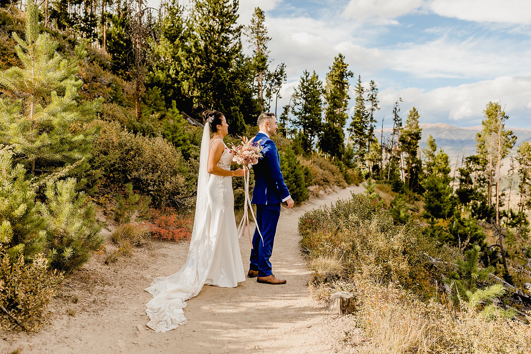 Bride and groom share first look for their breckenridge fall elopement surrounded by trees with beautiful mountains in the background