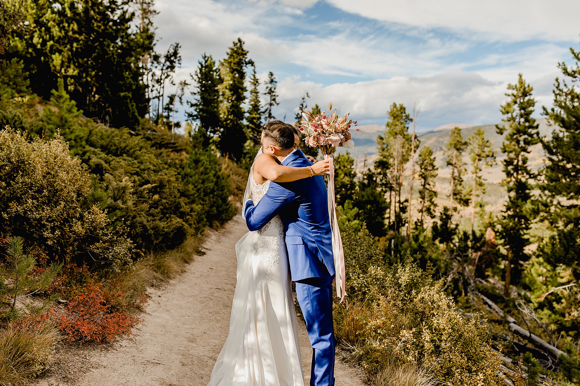 Bride and groom share first look for their breckenridge fall elopement surrounded by trees with beautiful mountains in the background