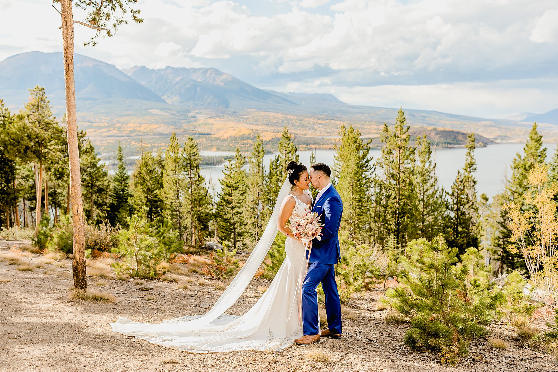 Couple stands in front of gorgeous mountain and lake views with changing aspens in the background for their breckenridge fall elopement, captured by Lauren Casino Photography, a Colorado elopement photographer