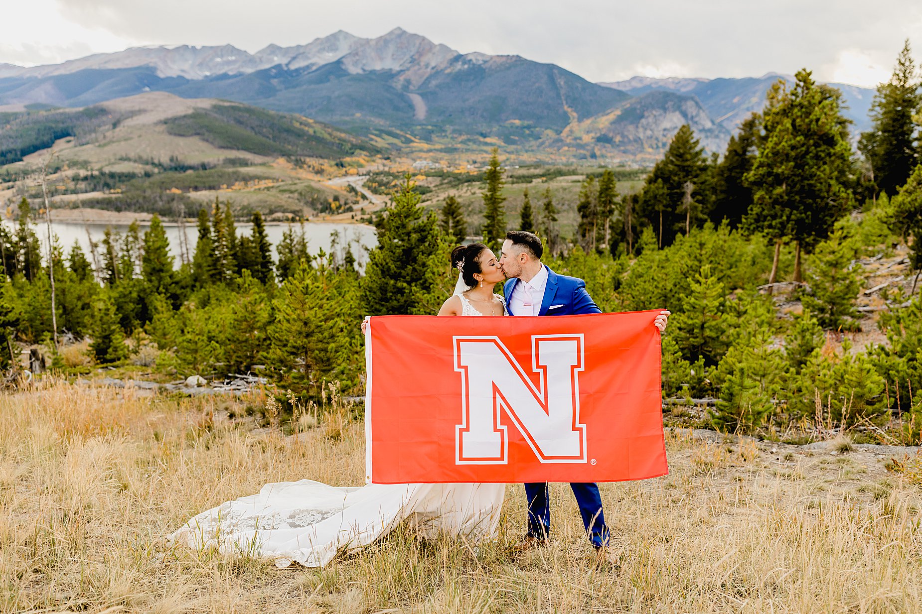 Bride and groom hold up their favorite sports team flag with stunning breckenridge mountain views in the background