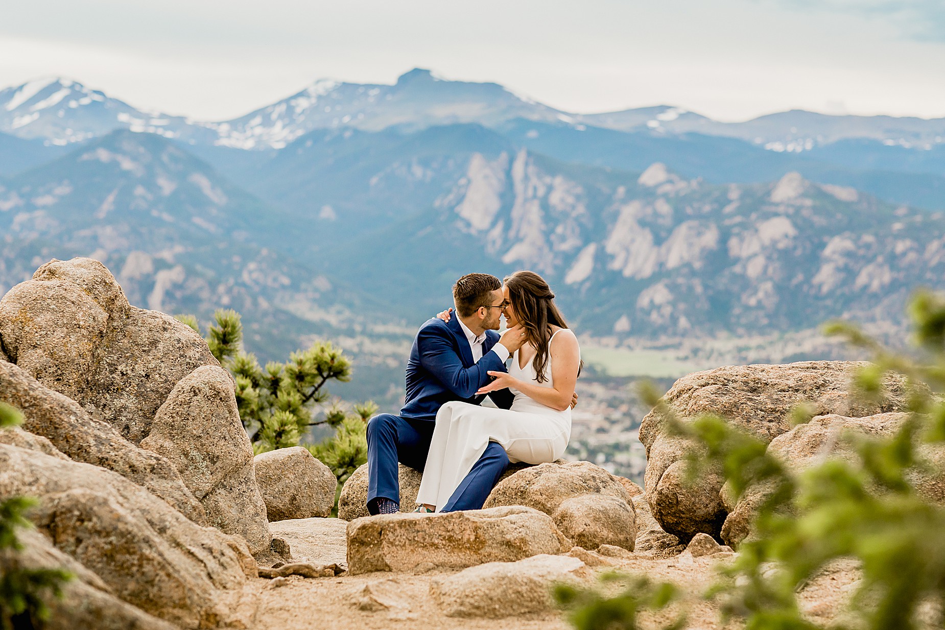 Couple sits on rocks together with stunning Rocky Mountain views for their Colorado hiking elopement