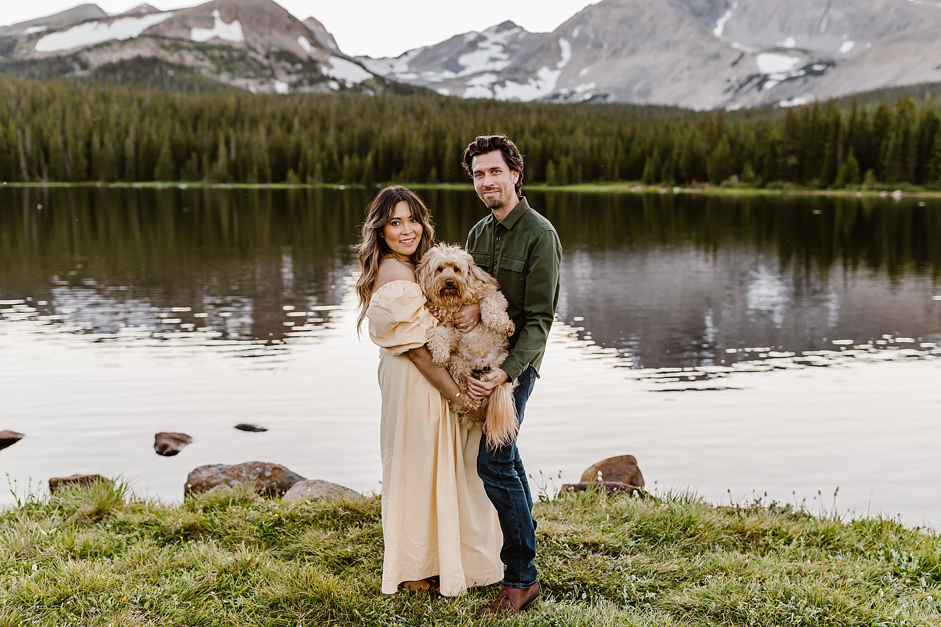Couple takes anniversary photos in the Rocky Mountains of Colorado with their dog in front of a beautiful mountain and alpine lake