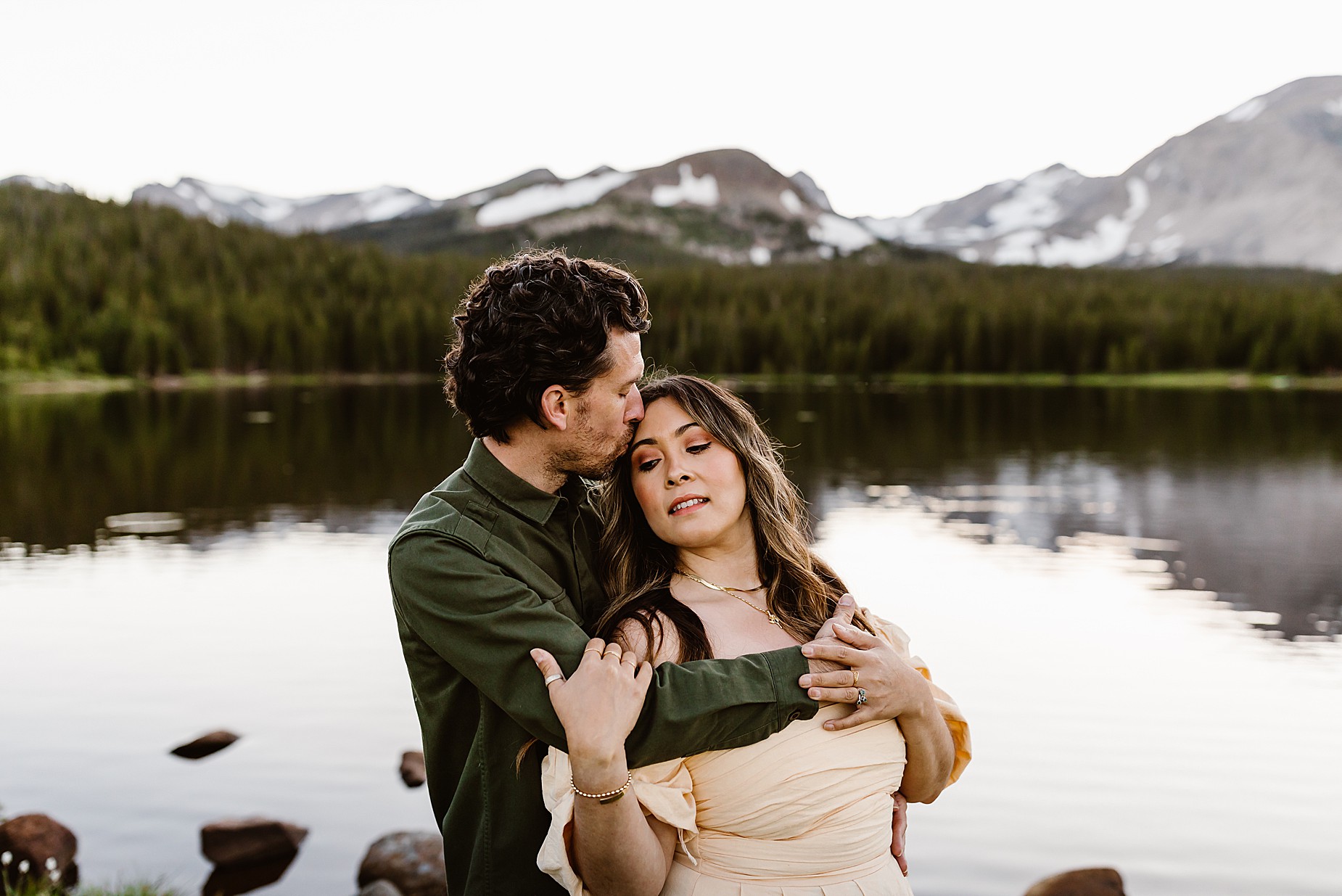 Couple takes Colorado anniversary photos in front of a beautiful mountain and alpine lake in the summer