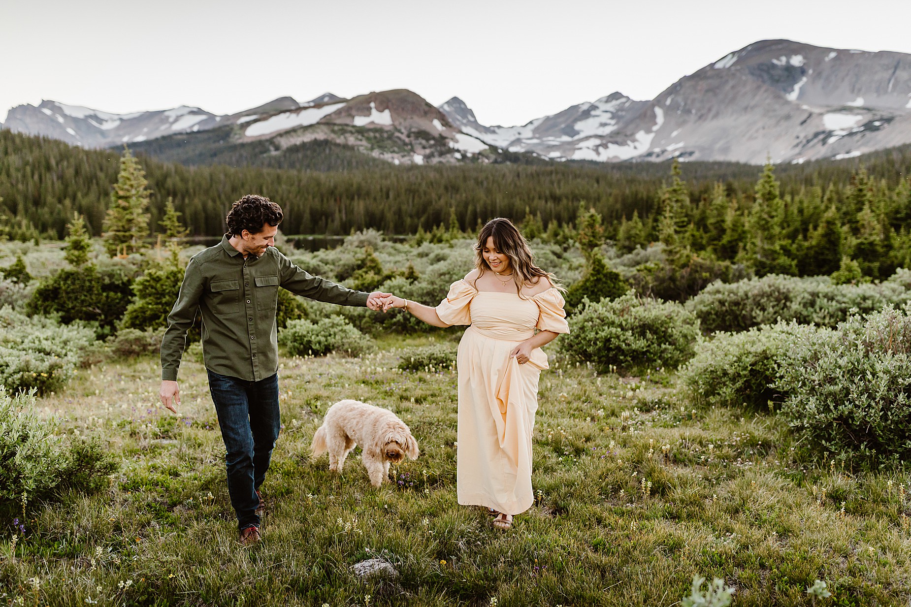 Couple takes anniversary photos in the Rocky Mountains of Colorado with their dog in front of a beautiful mountain and alpine lake